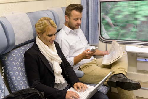 Photo: Woman with laptop man newspaper in train Woman with laptop man newspaper in train