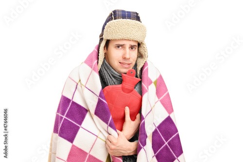 Photo: Sick man covered with blanket holding a hot-water bottle Sick man covered with blanket holding a hot-water bottle