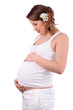 Happy pregnant woman with flower in hair holds belly isolated