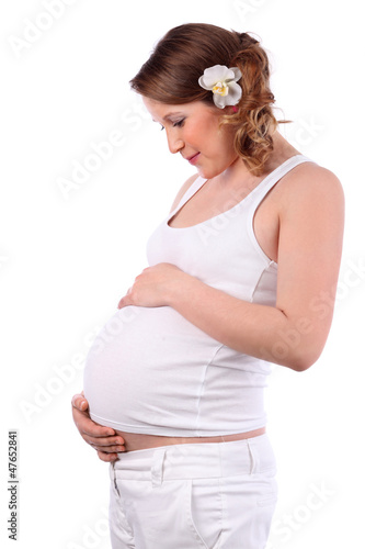 Photo: Happy pregnant woman with flower in hair holds belly isolated Happy pregnant woman with flower in hair holds belly isolated