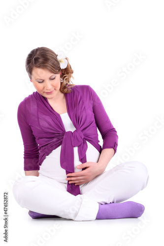 Photo: Pregnant woman sits on floor and holds her belly isolated Pregnant woman sits on floor and holds her belly isolated