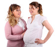 Pregnant woman in white and her girlfriend touching her stomach
