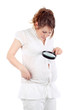 Pregnant woman in white looks through magnifying glass on belly