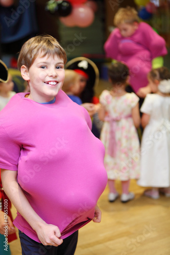 Photo: Smiling boy with balloons under pink shirt at children party. Smiling boy with balloons under pink shirt at children party.