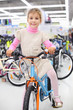 Smiling girl sits on bright bicycle and looks at camera