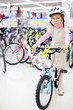 Serious girl in helmet sits on bright bicycle and looks
