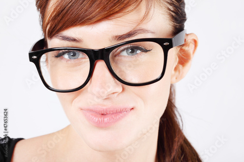 Photo: Beautiful woman in big black glasses smiles and looks at camera. Beautiful woman in big black glasses smiles and looks at camera.
