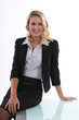 Businesswoman perched on her desk