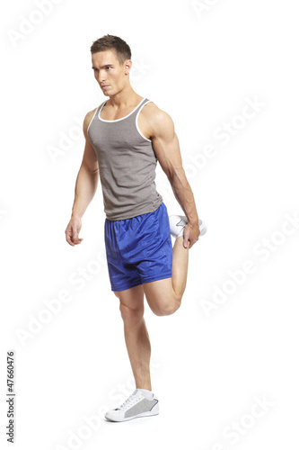 Photo: Muscular young man stretching in sports outfit Muscular young man stretching in sports outfit