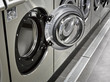 A row of industrial washing machines in a public laundromat