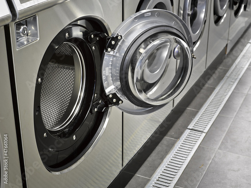 Photo: A row of industrial washing machines in a public laundromat A row of industrial washing machines in a public laundromat
