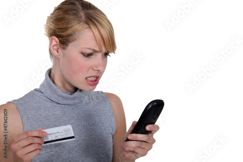 Photo: Edgy woman with credit card and telephone Edgy woman with credit card and telephone
