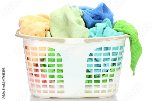 Photo: Plastic basket with bright towels isolated on white Plastic basket with bright towels isolated on white