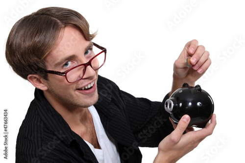 Photo: Nerd putting money in his piggy bank. Nerd putting money in his piggy bank.