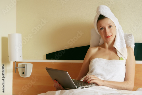 Photo: young business woman working at the note book in the bed young business woman working at the note book in the bed