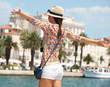 Happy young woman with outstretched hand and see on old town