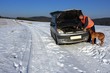 man repairing the car on a deserted road, winter weather