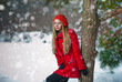 girl with cap and gloves playing with snow in the winter forest