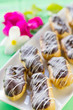 Photo: Chocolate éclairs on square white plate . Chocolate éclairs on square white plate .