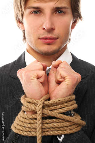 Photo: Handsome businessman hands tied with rope Handsome businessman hands tied with rope