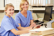 Two Nurses Working At Nurses Station
