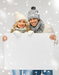 couple in a winter clothes holding blank board