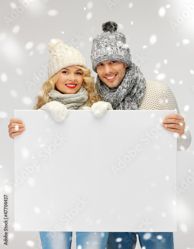 Photo: couple in a winter clothes holding blank board couple in a winter clothes holding blank board
