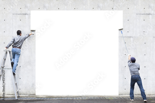 Photo: two workers are painting blank area on the wall two workers are painting blank area on the wall