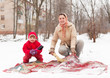  woman with child cleans rug  in winter day