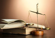 Gold scales of justice and books on brown background