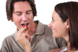 Woman offering piece of fruit to man