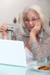 Old woman with credit card and computer