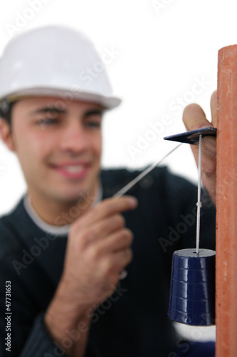 Photo: Mason using pendulum to check wall Mason using pendulum to check wall