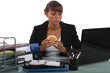 Woman eating a hamburger at her desk