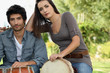 Couple playing bongo drums outdoors