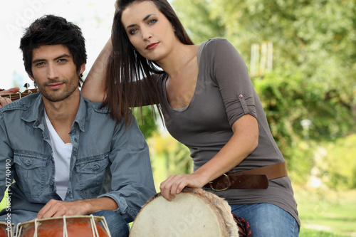 Photo: Couple playing bongo drums outdoors Couple playing bongo drums outdoors