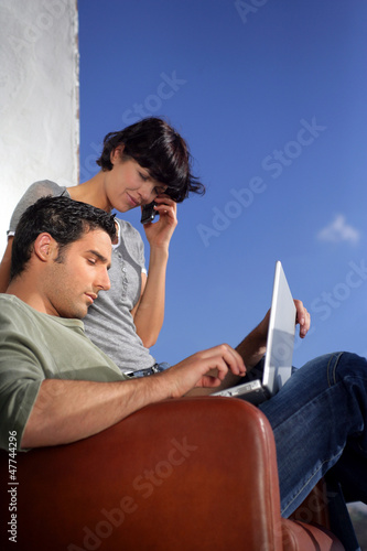 Photo: Couple sat outside wuth laptop Couple sat outside wuth laptop