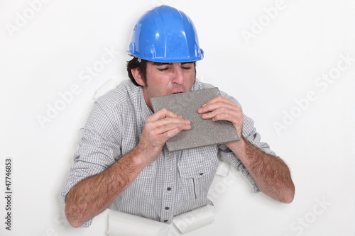 Photo: Fed-up tradesman biting a tile Fed-up tradesman biting a tile