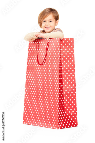 Photo: A smiling child posing in a red spotted shopping bag A smiling child posing in a red spotted shopping bag