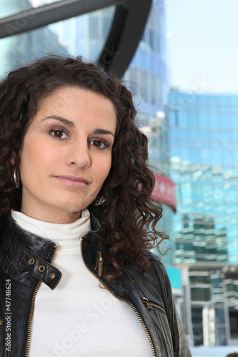 Photo: Uncertain woman standing in front of a modern building Uncertain woman standing in front of a modern building