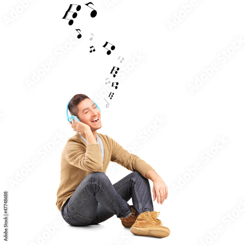 Photo: Guy on a floor listening music on headphones and notes around hi Guy on a floor listening music on headphones and notes around hi
