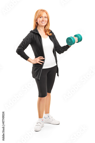 Photo: Full length portrait of a mature woman lifting up a dumbbell Full length portrait of a mature woman lifting up a dumbbell