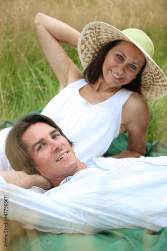 Photo: 40 years old man and woman relaxing and lying down in a meadow 40 years old man and woman relaxing and lying down in a meadow