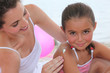 Mother putting suncream on her daughter.