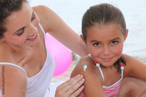 Photo: Mother putting suncream on her daughter. Mother putting suncream on her daughter.