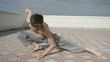 Man practices yoga on the roof. Squat on one leg.