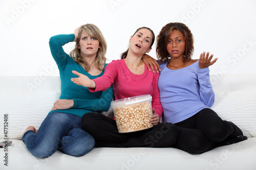 Photo: friends watching television and eating popcorn friends watching television and eating popcorn