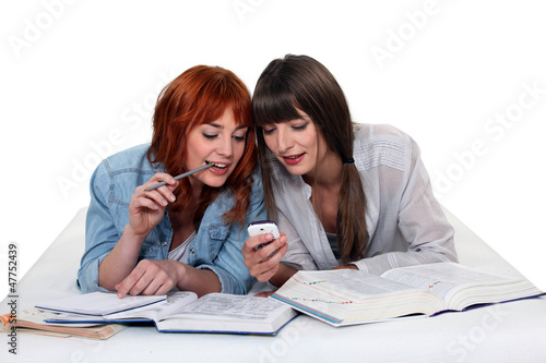 Photo: Young women taking a break from studying to read a text message Young women taking a break from studying to read a text message