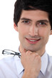 Close-up portrait of a smiling man holding his glasses