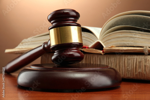 Photo: wooden gavel and books on wooden table,on brown background wooden gavel and books on wooden table,on brown background